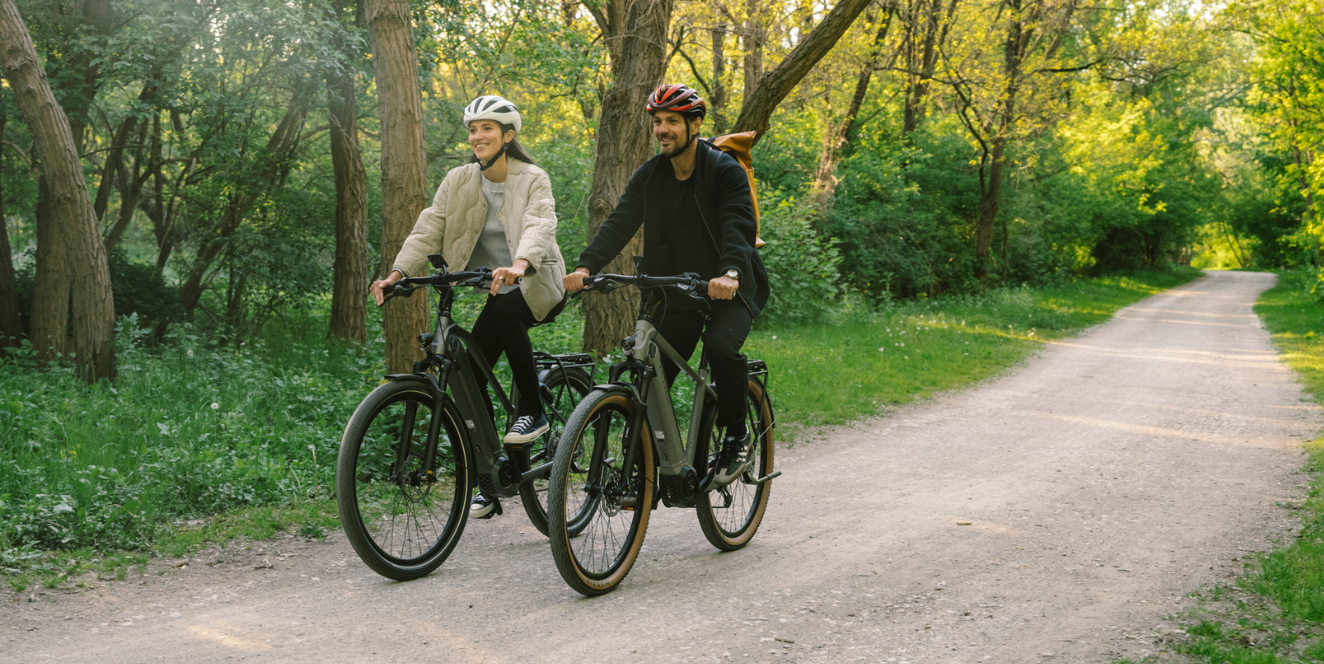 2 Menschen fahren Fahrrad durch einen Wald