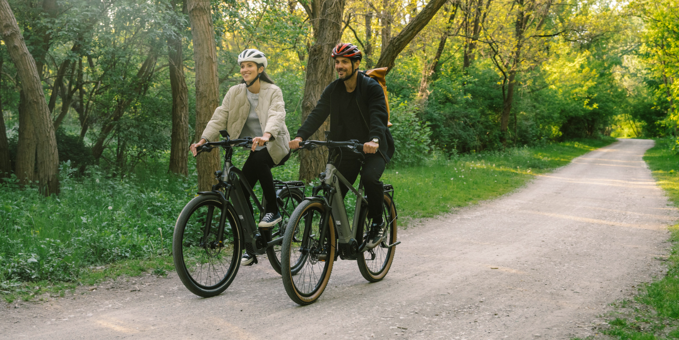 Kalkhoff-E-Bikes-Sale 2 Menschen fahren Fahrrad durch einen Wald